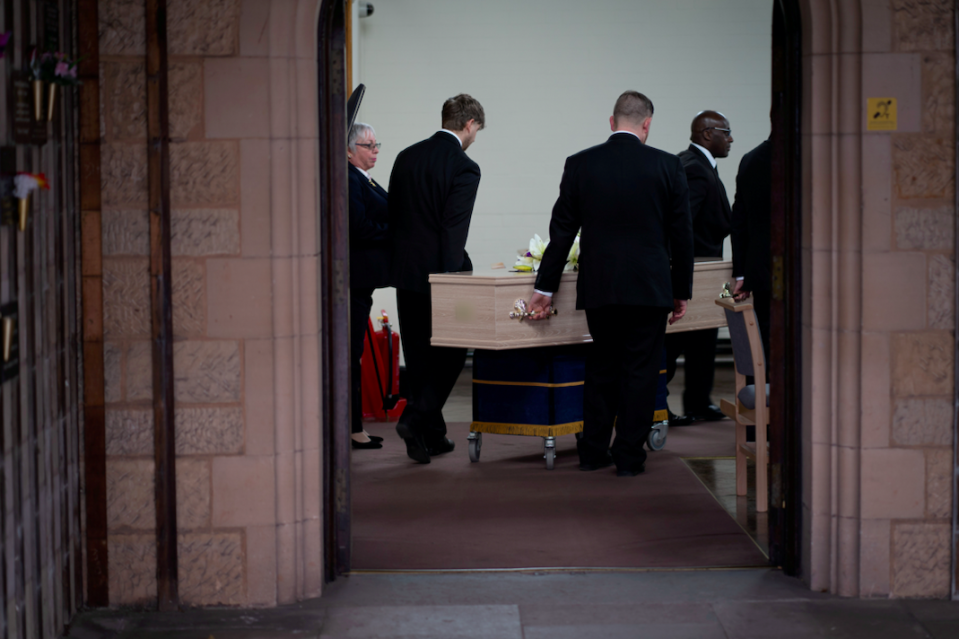 Funeral staff take the coffins away following the service.