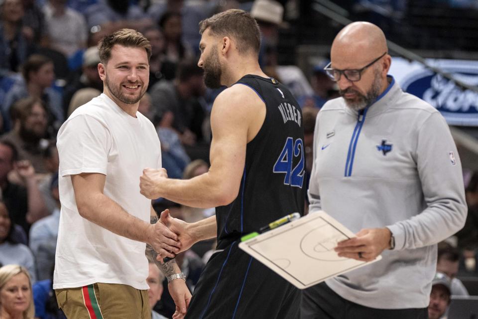 Dallas Mavericks' Luka Doncic, left, who was not playing due to ankle soreness, congratulates forward Maxi Kleber (42) as head coach Jason Kidd walks off the court during the first half of an NBA basketball game against the Detroit Pistons, Friday, April 12, 2024, in Dallas. (AP Photo/Jeffrey McWhorter)
