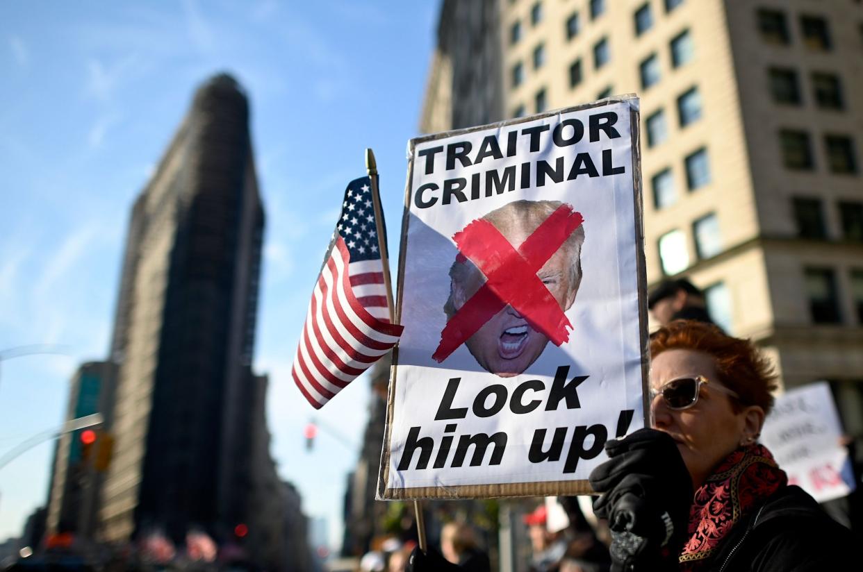 A protester holding a sign reading 'Traitor, Criminal, Lock him up!' close to where President Donald Trump is giving a speech at Madison Square Park in New York City to mark Veterans Day: AFP via Getty Images