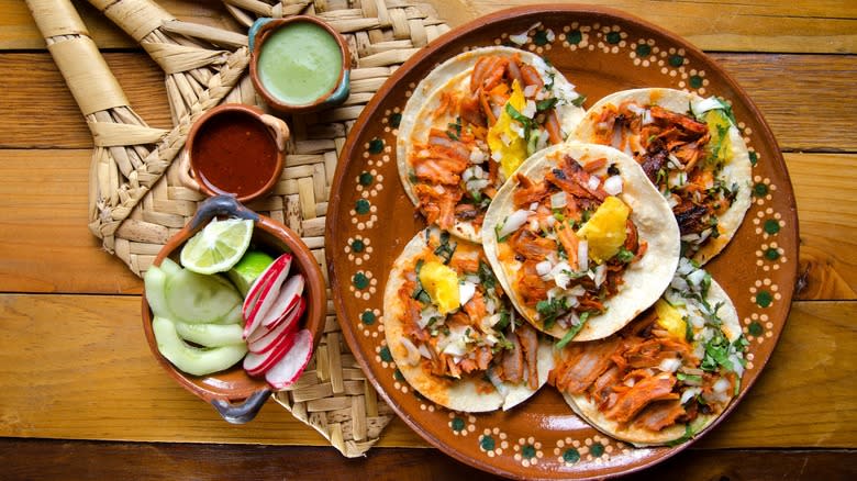 Top-down view of al pastor and pineapple chunks atop tacos on plate