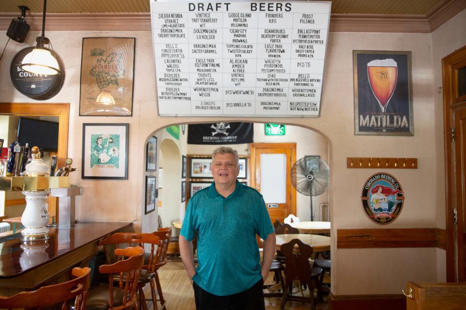 Mike Romans poses for a portrait in his pub, Roman's Pub, underneath a draft beer sign that he writes by hand, on Friday, July 19, 2019. Romans purchased the bar in 1978 he says because, "if I was going to work that hard I might as well own my own bar."