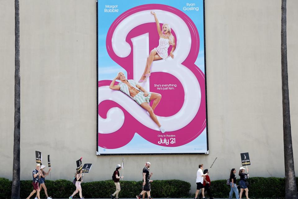 Striking SAG-AFTRA members picket with striking WGA workers near a billboard for the 'Barbie' movie outside Warner Bros. Studio on July 17, 2023, in Burbank, California. 