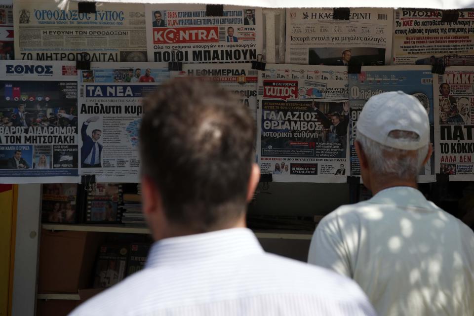 People read the front pages of the Greek newspapers as all of them refer to the election result in Athens, Monday, July 8, 2019. Conservative party leader Kyriakos Mitsotakis' New Democracy party won 39.8% of the Sunday vote, giving him 158 seats in the 300-member parliament, a comfortable governing majority. (AP Photo/Thanassis Stavrakis)