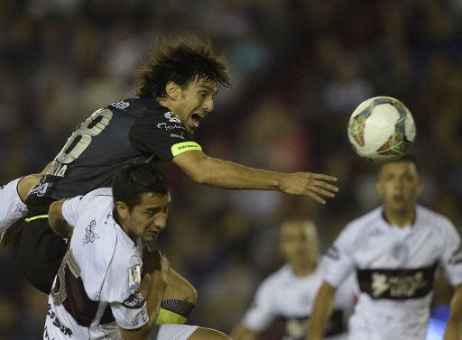 El defensa del mexicano Santos Laguna, Jonathan Lacerda (arriba), cabecea sobre el volante del argentino Lanús, Diego González, durante partido de ida de octavos de final de la Copa Libertadores 2014, en el estadio de Lanús, en Buenos Aires, Argentina, el 16 de abril de 2014. (AFP | Juan Mabromata)