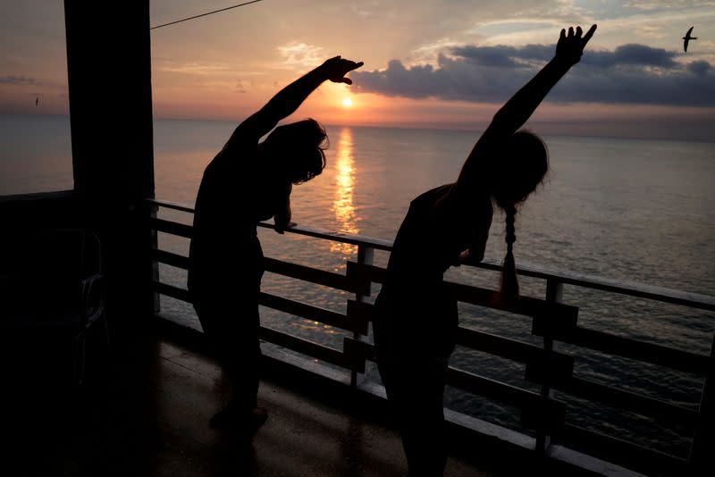 Foto de los bailarines clásicos Leticia Silva and Alejandro Silva actuando para una cámara de TV (fuera de la imagen) en el balcón de su departamento en La Habana, en medio de la pandemia del coronavirus