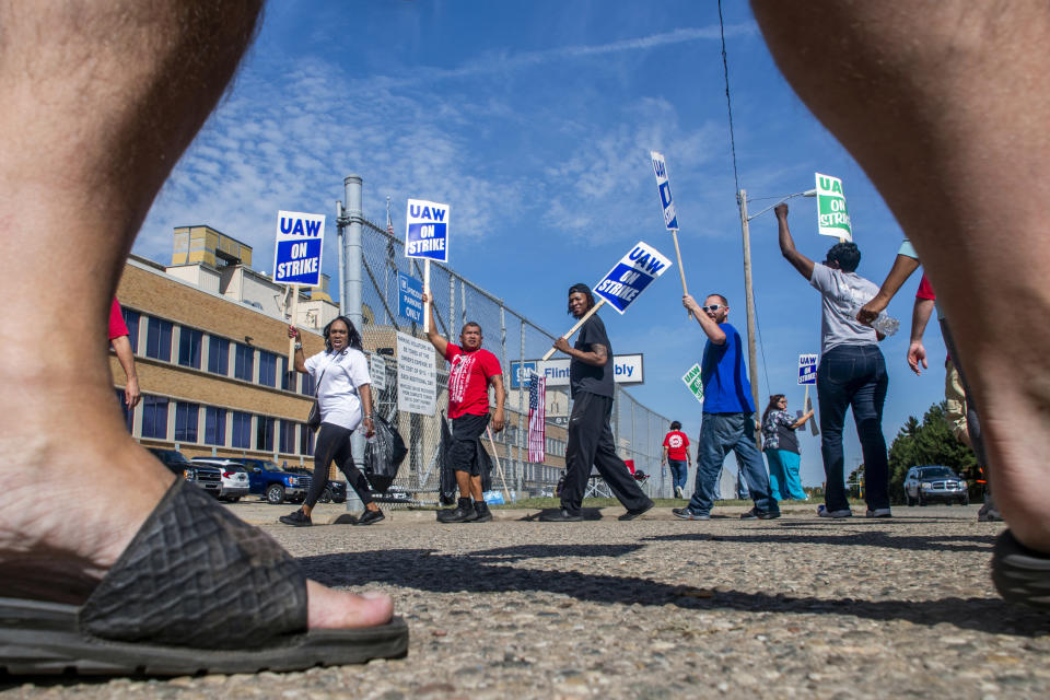 White Lake resident D.J. Calma of White Lake, second from left and has worked for General Motors in four different plants in 12 years, chants in unison "No contract! No work!" as they circle at one of the Flint Assembly Plant entrance, blocking through traffic during the fourth day of the national UAW strike against GM on Thursday, Sept. 19, 2019 in Flint. The United Auto Workers union and its roughly 49,000 members at GM plants in the U.S. have been on strike since Monday, Sept. 16 because contract negotiations with the automaker had broken down. It's the first national UAW strike since 2007, when GM workers were out for two days. (Jake May/The Flint Journal via AP)