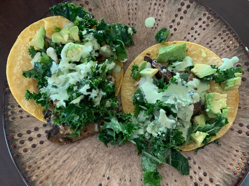 two tacos with avocado on brown plate