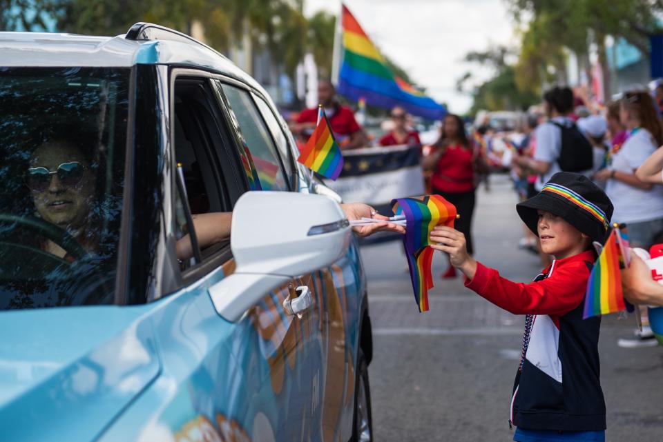 A young parade-goer receives a pride flag from a parade participant during the Palm Beach Pride Parade, held Sunday in downtown Lake Worth Beach. Thousands attended the parade, which featured dozens of floats, officials and groups celebrating LGBTQ pride while marching east along Lake Avenue to Bryant Park.