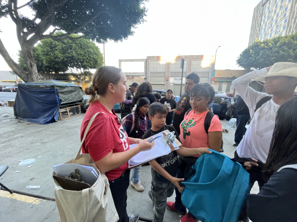 A woman in a red shirt talks to workers outside Union Rescue Mission