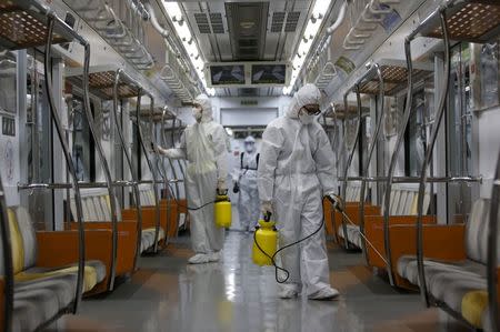 Workers in full protective gear disinfect the interior of a subway train at a Seoul Metro's railway vehicle base in Goyang, South Korea, June 9, 2015. REUTERS/Kim Hong-Ji