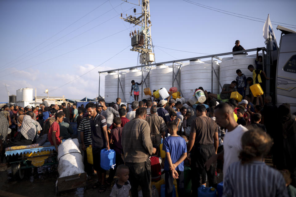 Palestinians displaced by the Israeli bombardment of the Gaza Strip queue for water at a makeshift tent camp in the southern town of Khan Younis, Monday, July 1, 2024. (AP Photo/Jehad Alshrafi)