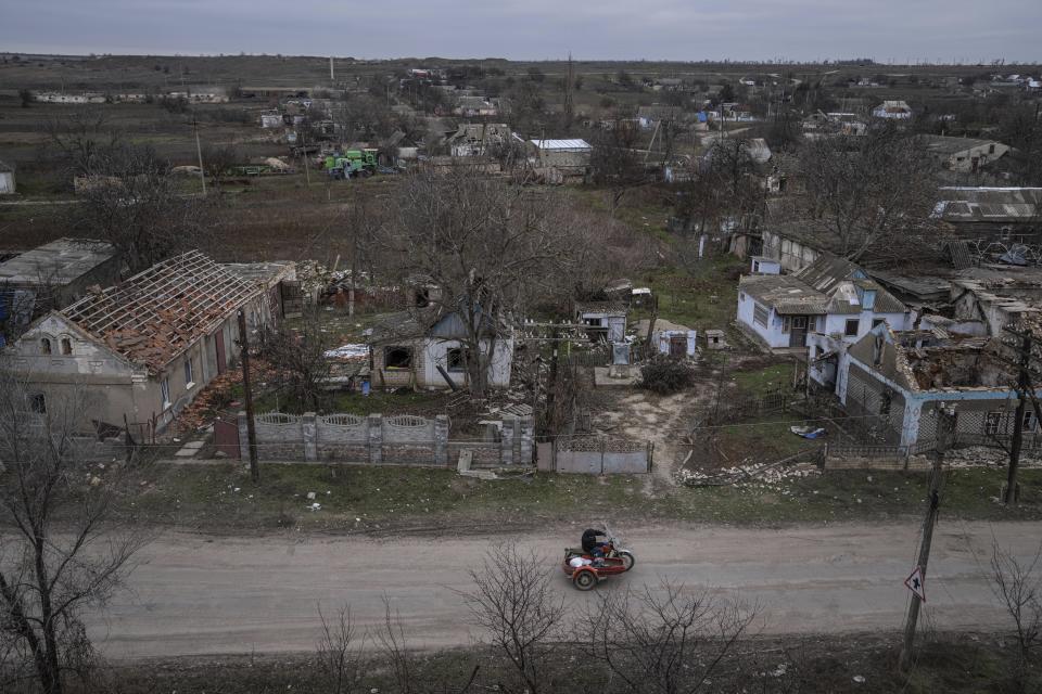 Un hombre en motocicleta pasa el lunes 5 de diciembre de 2022 frente a casas que han sido destruidas durante los enfrentamientos entre las fuerzas rusas y las ucranianas, en Arhanhelske, Ucrania. (AP Foto/Evgeniy Maloletka)