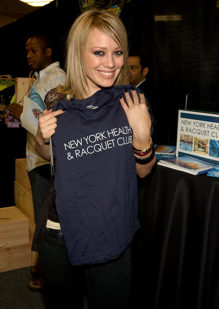 Hilary holding up a New York Health & Racquet Club T-shirt