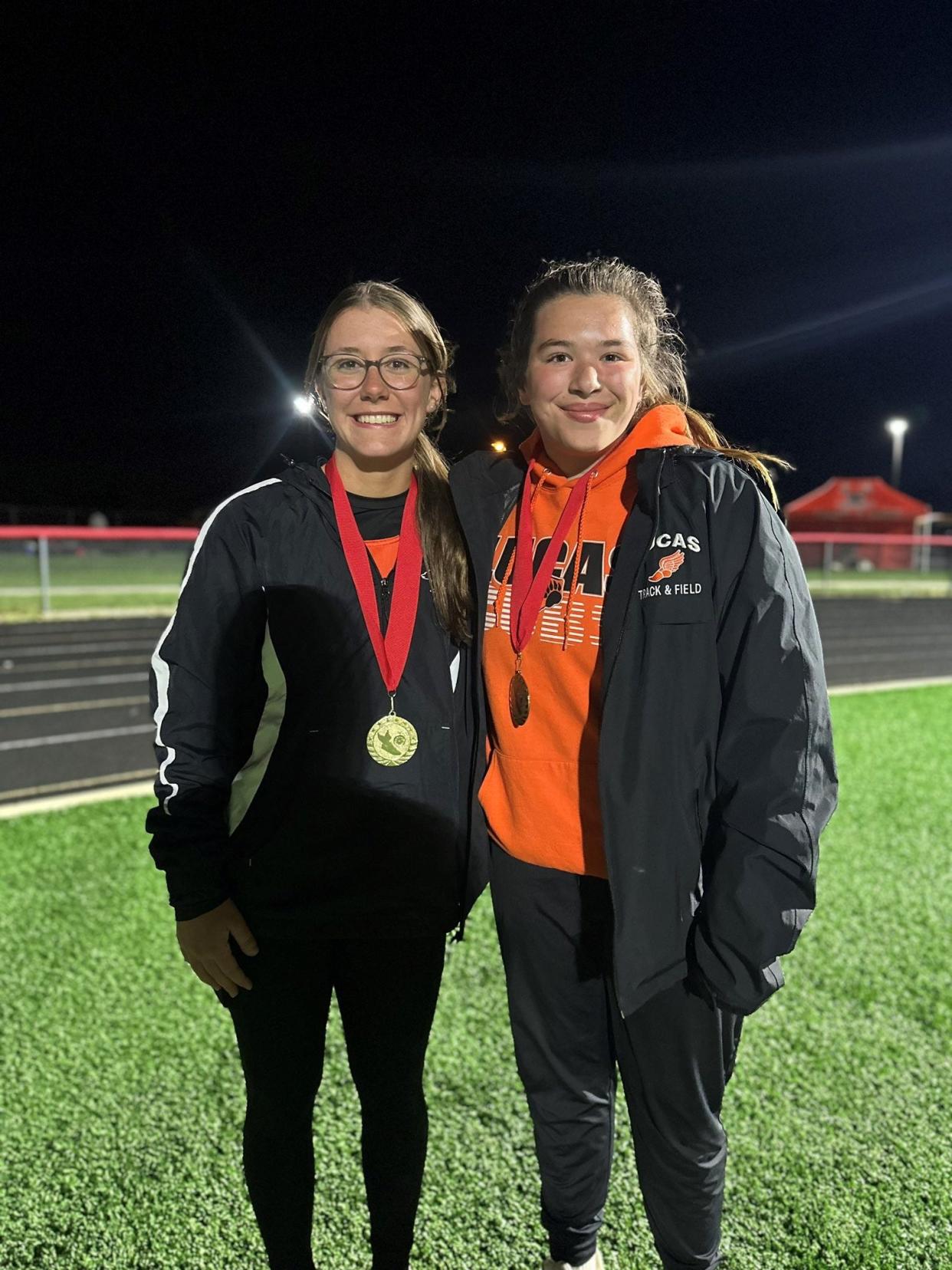Lucas' Rebekah Case (left) and Katie Griffey (right) pose with their medals for winning events during the Forest Pruner Invite on Friday night.