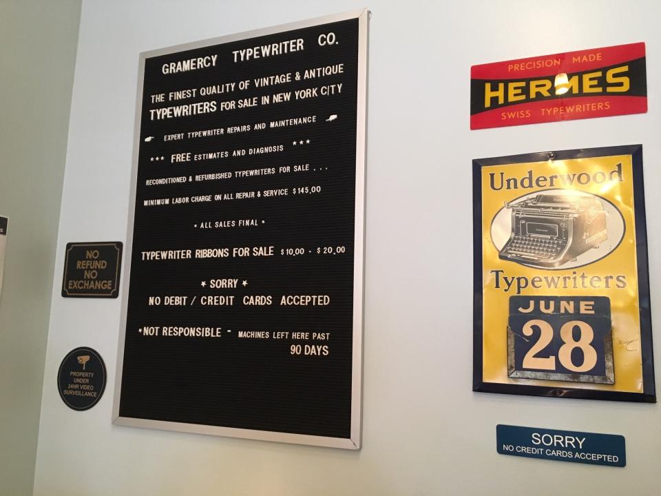 This June 28, 2019 photo shows signs on the wall of the Gramercy Typewriter Co. in New York, which sells working vintage typewriters and ribbons for them, and repairs vintage typewriters. Vintage typewriters are sent for repair and restoration daily from around the country, the owner says. (Katherine Roth via AP)