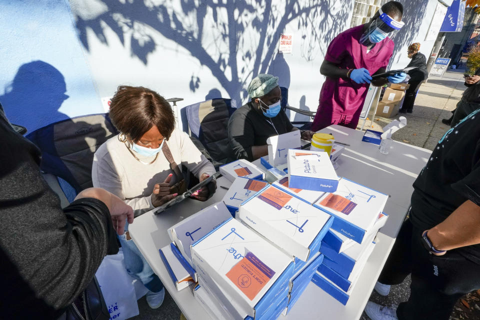 FILE - In this Nov. 10, 2020, Tia Richardson, seated left, Gracelyn Morris, center, and Kenned Yakpoh record information from residents before administering coronavirus tests at the Central Family Life Center, in the Stapleton neighborhood of the Staten Island borough of New York. School systems in several states are giving up on in-person classes, and some governors are reimposing restrictions on bars and restaurants or getting more serious about masks, as the coast-to-coast resurgence of the coronavirus sends deaths, hospitalizations and new infections soaring. (AP Photo/Mary Altaffer, File)