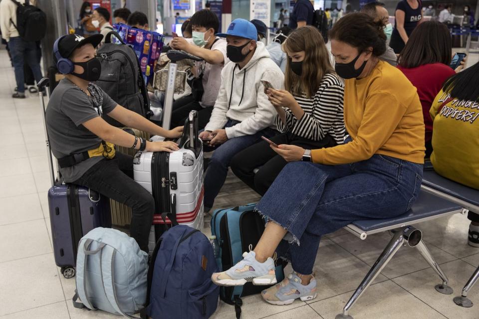 family traveling sitting in airport wearing masks