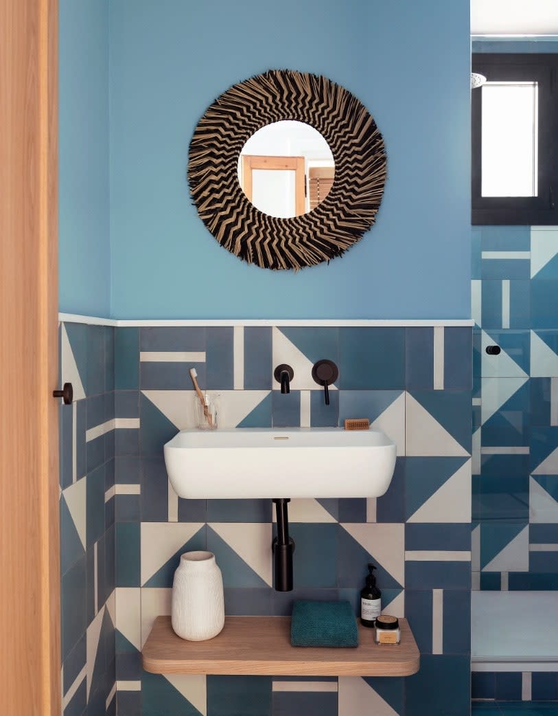 In the blue bathroom, the geometric tiles were made to measure and contrast with the curved mirror by Kave Home.