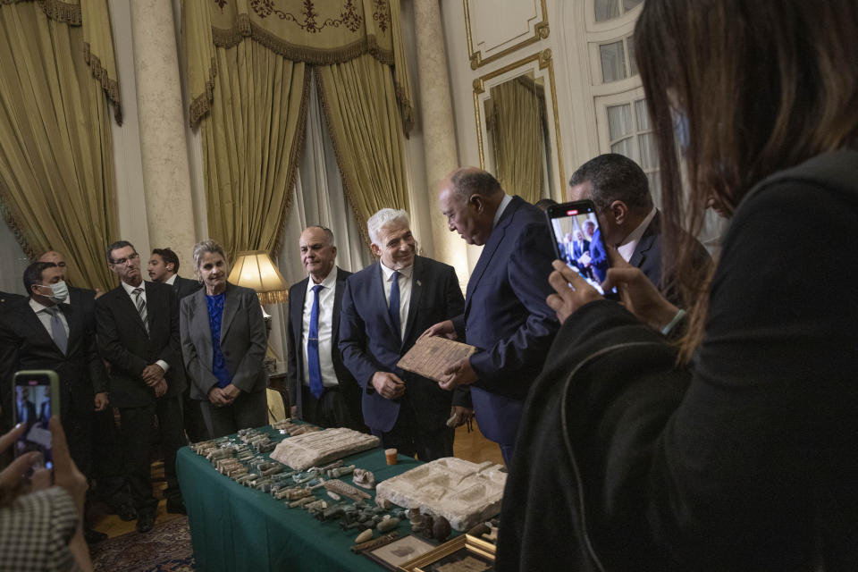 Israeli Foreign Minister Yair Lapid, presents Egyptian Foreign Minister Sameh Shoukry with stolen Egyptian artifacts that were smuggled to Israel and returned back to Egypt, at Tahrir Palace in Cairo, Egypt, Thursday, Dec. 9, 2021. (AP Photo/Nariman El-Mofty)