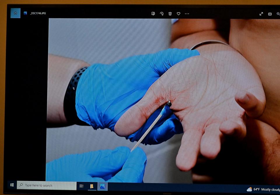 A monitor displays an evidence photo of Carlos Asencio's hand.