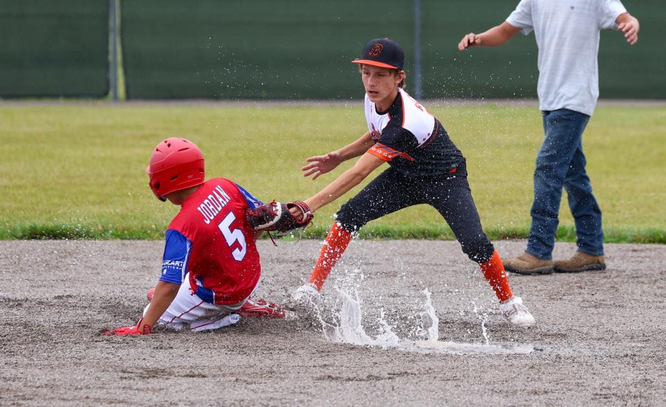 Monroe's Rudy Jordan slides through water and mud but is tagged out by Kaiden Raymo of Summerfield Saturday during the opening day of the 63rd annual Monroe County Fair Baseball Tournament.