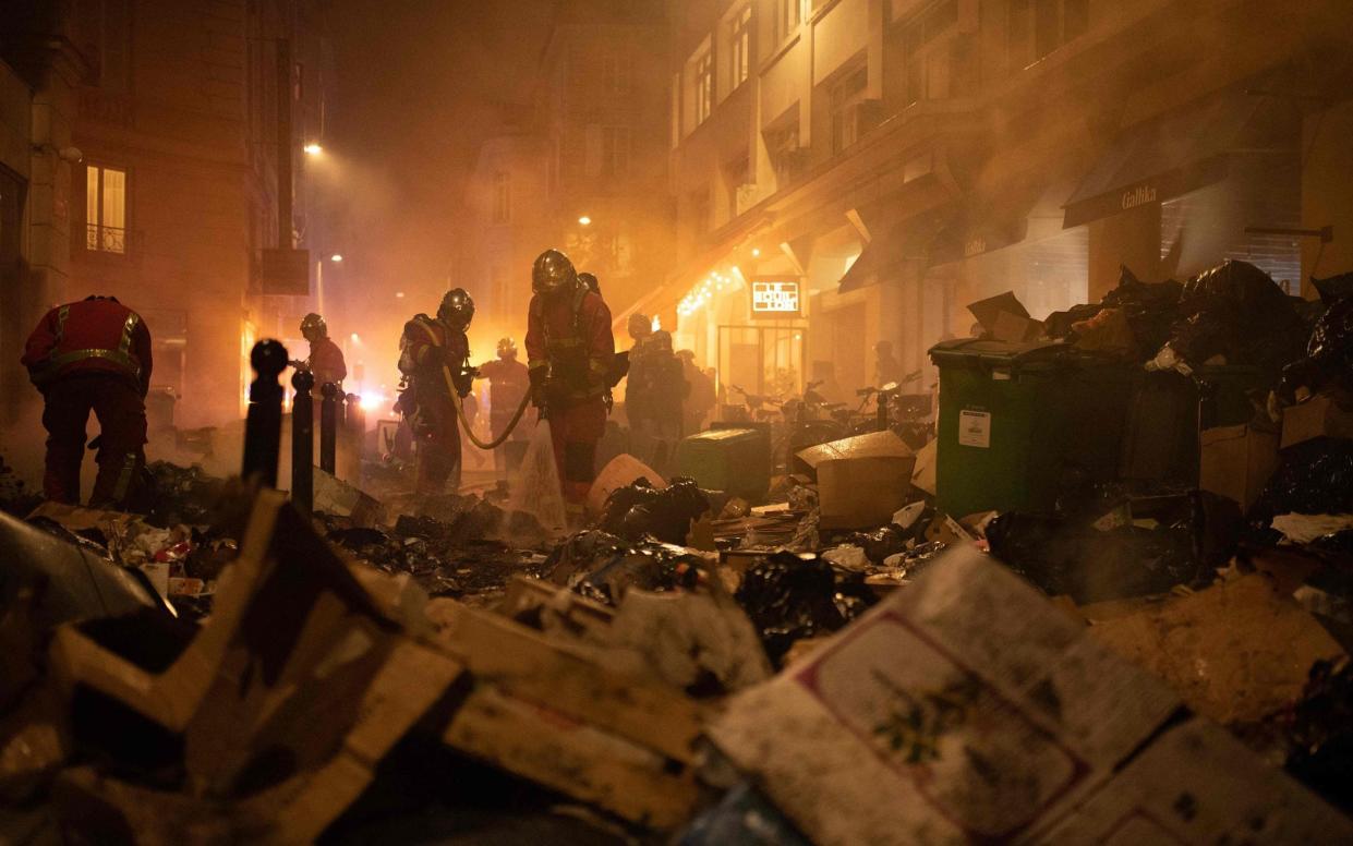 Firefighters check rubbish after extinguishing a fire during a demonstration - ANNA KURTH