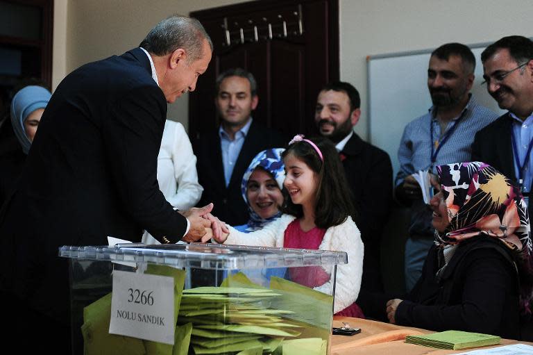 Turkish President Recep Tayyip Erdogan (L) shakes hands with a girl after voting in Turkey's general election at a polling station in Istanbul on June 7, 2015