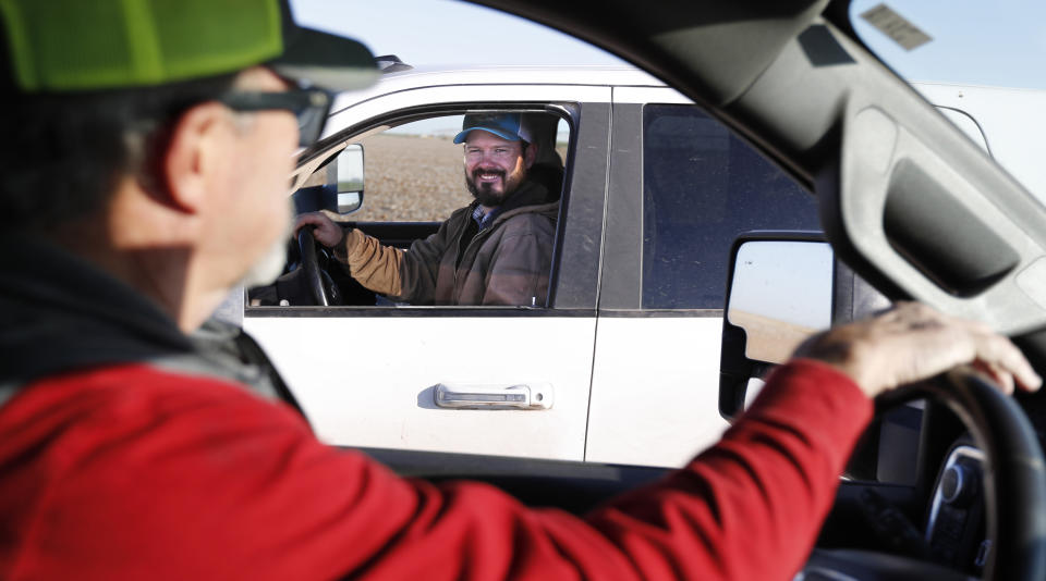 Tim Black, left, stops to talk to his son, Tyler, on their farm in Muleshoe, Texas, on Monday, April 19, 2021. The longtime corn farmers now raise cattle and have planted some land in wheat and native grasses because the Ogallala Aquifer, used to irrigate crops, is drying up. (AP Photo/Mark Rogers)