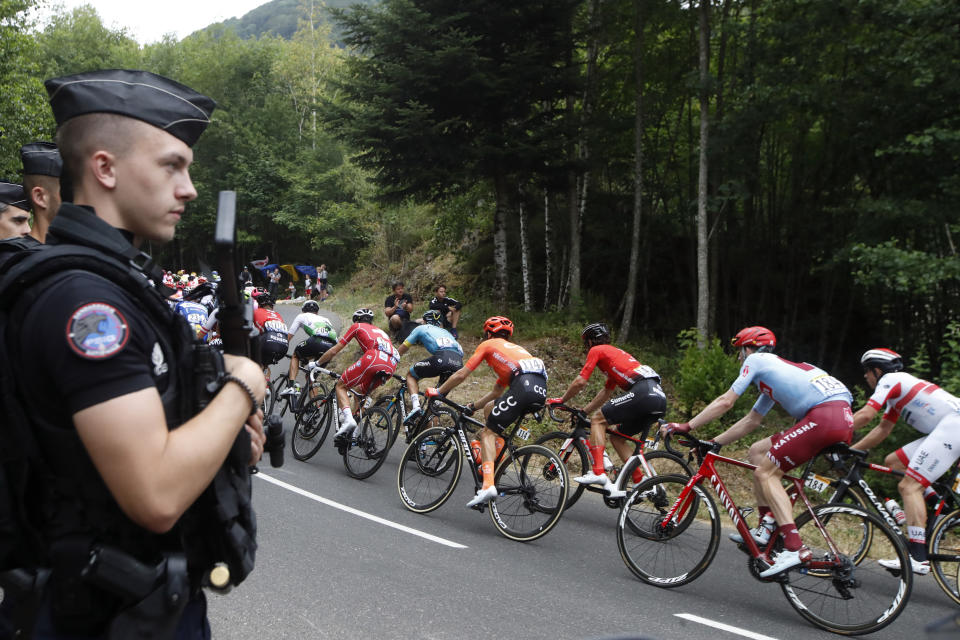 The pack rides past police officers during the sixth stage of the Tour de France cycling race over 160 kilometers (100 miles) with start in Mulhouse and finish in La Planche des Belles Filles, France, Thursday, July 11, 2019. (AP Photo/Christophe Ena)