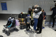 Members of the Mogul family, a father hugs his daughter, who arrived with her son, bottom left, on a flight from Charlotte, North Carolina, in the U.S., at Terminal 5 of Heathrow Airport in London, Monday, Aug. 2, 2021. Travelers fully vaccinated against coronavirus from the United States and much of Europe were able to enter Britain without quarantining starting today, a move welcomed by Britain's ailing travel industry. (AP Photo/Matt Dunham)