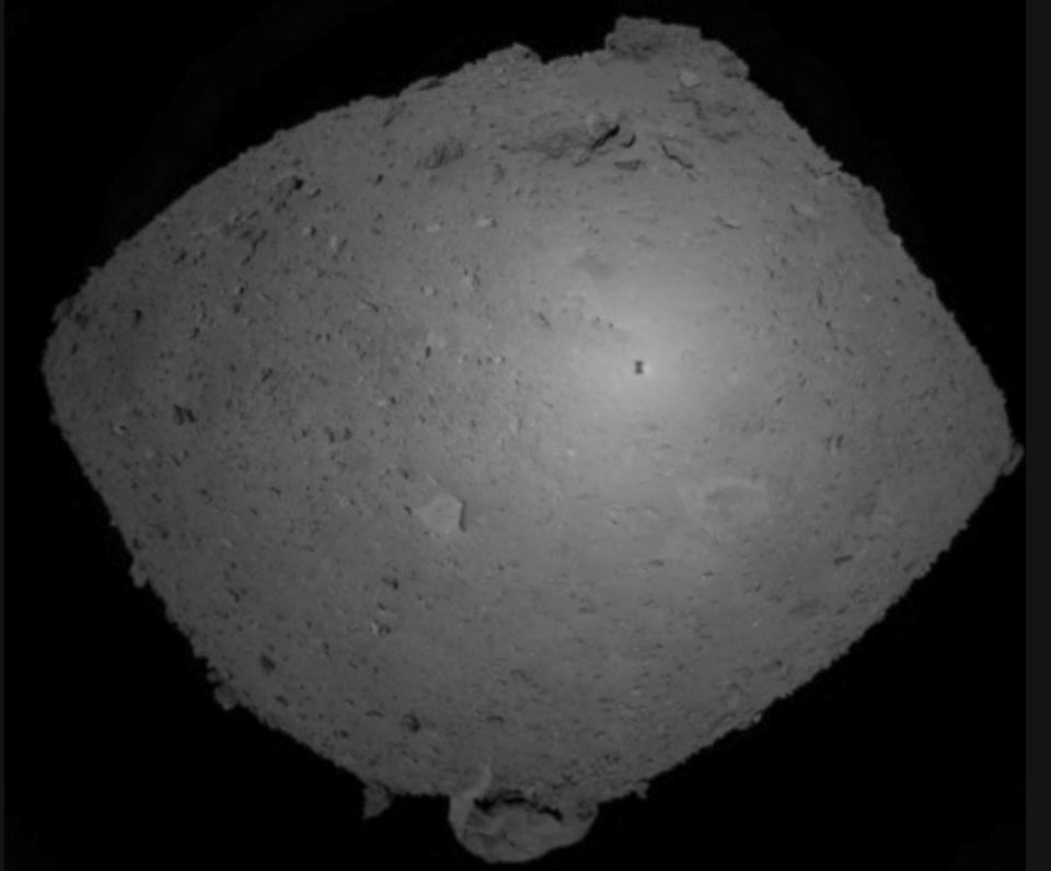 This Oct. 25, 2018, image provided by the Japan Aerospace Exploration Agency (JAXA) shows asteroid Ryugu. Japanese spacecraft Hayabusa2 is approaching the surface of an asteroid about 280 million kilometers (170 million miles) from Earth. The JAXA said Thursday, Feb. 21, 2019, that Hayabusa2 began its approach at 1:15 p.m. Hayabusa2's shadow is seen at center right over Ryugu. (JAXA via AP)