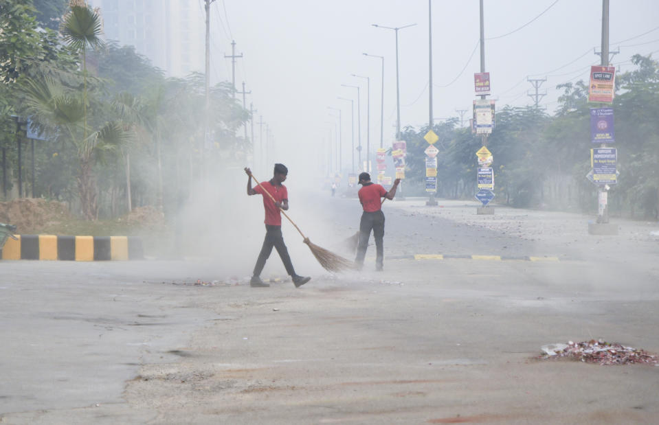 Indian workers are seen in the morning smog as they clean a lane littered with remains of firecrackers set off Wednesday night in Greater Noida, near New Delhi, India, Thursday, Nov.8, 2018. Toxic smog shrouded the Indian capital as air quality plummeted to hazardous levels Thursday after tens of thousands of people set off a multitude of firecrackers to celebrate the major Hindu festival of Diwali. (AP Photo/R S Iyer)