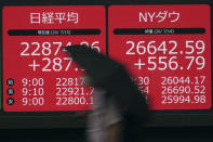 A man walks past an electronic stock board showing Japan's Nikkei 225 and New York Dow indexes at a securities firm in Tokyo Wednesday, July 15, 2020. Shares were mostly higher in Asia on Wednesday as investors were encouraged by news that an experimental COVID-19 vaccine under development by Moderna and the U.S. National Institutes of Health revved up people’s immune systems just as desired. (AP Photo/Eugene Hoshiko)