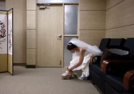 A bride puts on her shoes for a wedding ceremony at a budget wedding hall at the National Library of Korea in Seoul, South Korea, May 16, 2015. REUTERS/Kim Hong-Ji