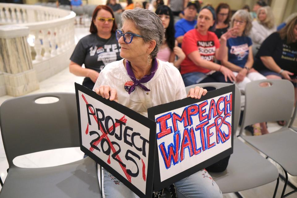 A woman holds signs at the Impeach Ryan Walters rally Saturday on the second floor of the Oklahoma Capitol.