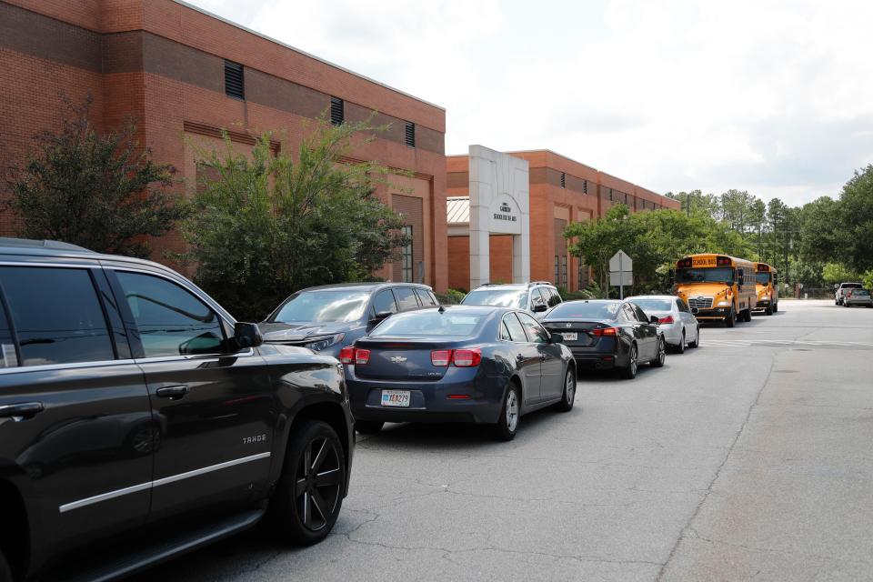 A few buses and a line of cars wait to pick up students from Garrison School for the Arts during Summer Embrace. As one of the Choice School programs Garrison will have very limited busing available for families during next school year.