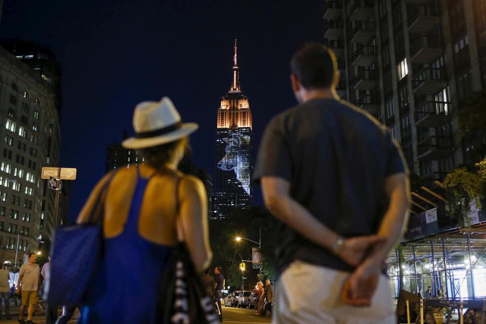 People watch as an image of an animal is projected onto the Empire State Building as part of an endangered species projection to raise awareness, in New York August 1, 2015. (REUTERS/Eduardo Munoz)