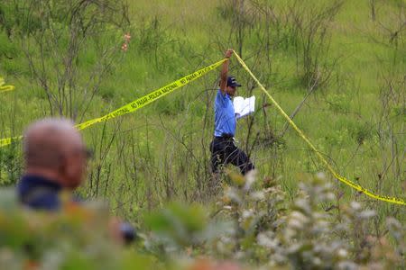 FILE PHOTO: A police officer cordons off a clandestine cemetery that was recently discovered in El Lolo neighbourhood, on the outskirts of Tegucigalpa, Honduras, July 21, 2017. REUTERS/Jorge Cabrera/File Photo