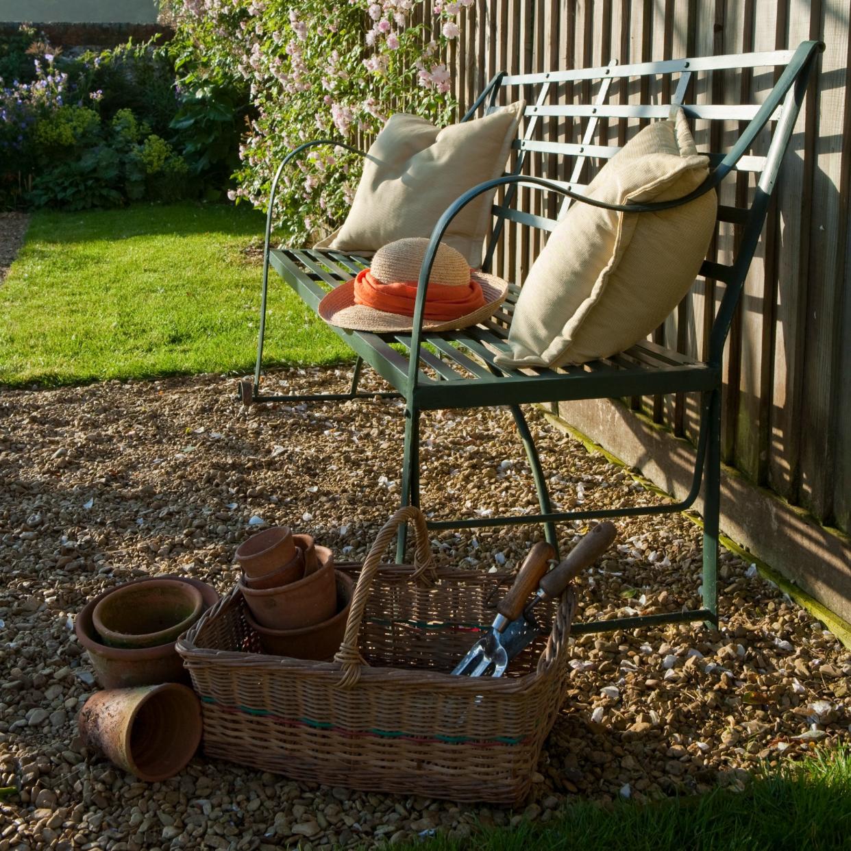  A garden with a bench and a basket filled with tools. 