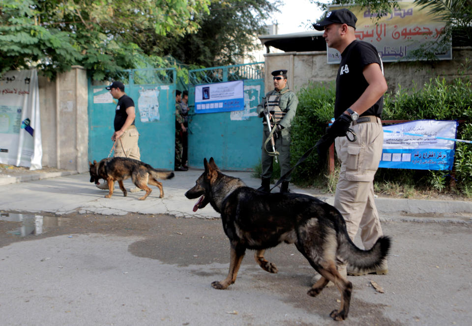 Security forces and their dogs stand guard outside a polling center in Baghdad, Iraq, Monday, April 28, 2014. Amid tight security, some one million Iraqi army and police personnel have started voting for the nation's new parliament. (AP Photo/ Khalid Mohammed)