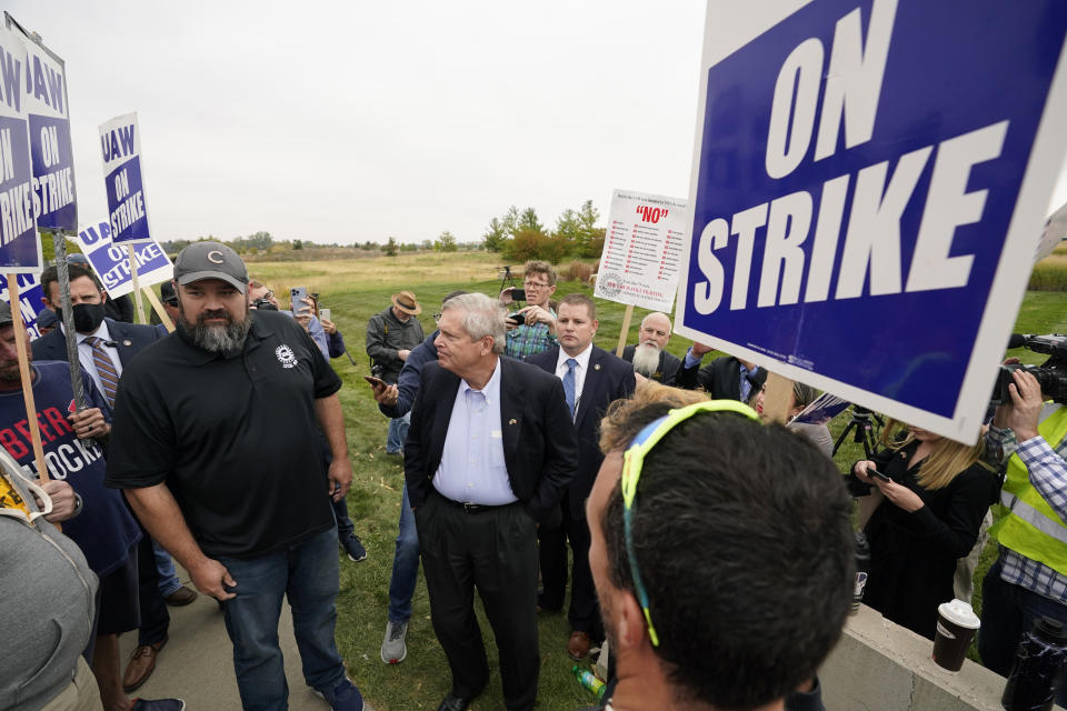 Agriculture Secretary Tom Vilsack and United Auto Workers Local 450 Vice President Justin Limke, left, talk with members of the UAW outside of a John Deere plant, Wednesday, Oct. 20, 2021, in Ankeny, Iowa. About 10,000 UAW workers have gone on strike against John Deere since last Thursday at plants in Iowa, Illinois and Kansas. (AP Photo/Charlie Neibergall)