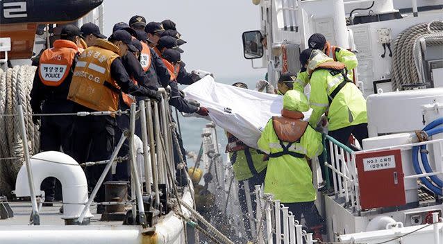 South Korean Coast Guard police officers on a boat carry the body of a passenger believed to have been trapped in the sunken ferry Sewol in the water off the southern coast near Jindo, south of Seoul, South Korea. Photo: AP.