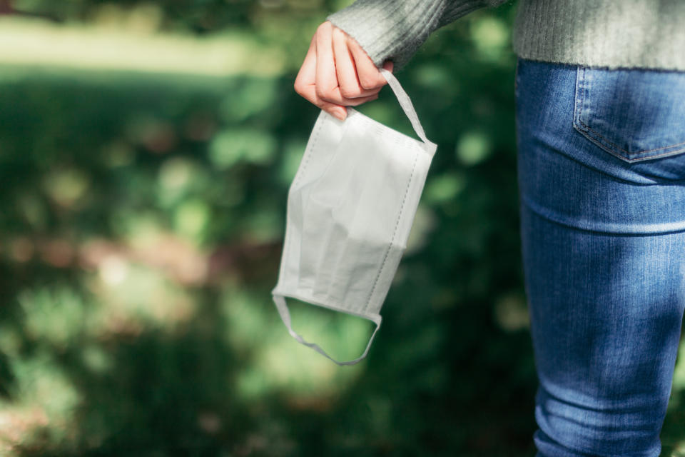 Cropped shot of the rear view of a woman taking off her protective face mask while walking at the park, enjoying a virus-free zone when coronavirus has ended.