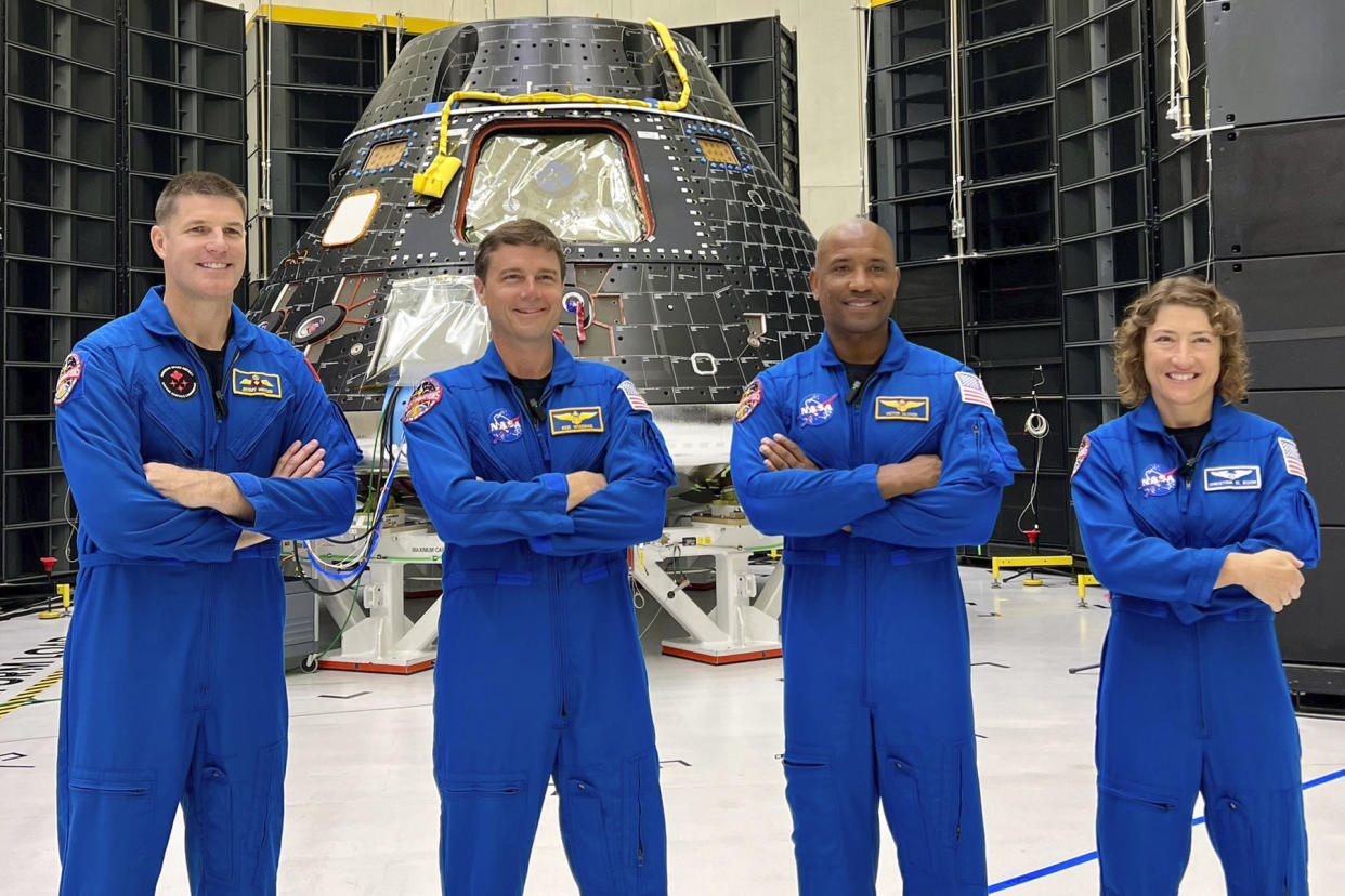 This photo posted on X, formerly known as Twitter, on Tuesday, Aug. 8, 2023, shows astronauts, from left, Jeremy Hansen, Reid Wiseman, Victor Glover and Christina Koch at Florida's Kennedy Space Center. The four, who will fly to the moon in 2024, have gotten their first up-close look at their spacecraft, the Orion capsule, background, during a visit on late Monday and Tuesday. (NASA via AP)