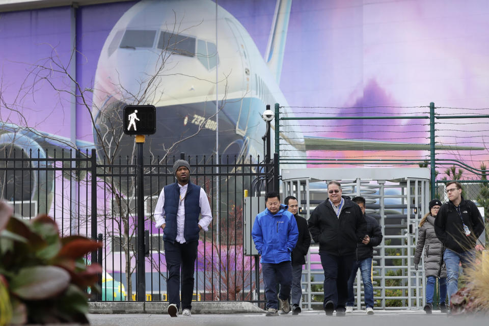 Boeing workers exit the plant in front of a giant mural of a jet on the side of the manufacturing building behind Monday, Dec. 16, 2019, in Renton, Wash. Shares of Boeing fell before the opening bell on a report that the company may cut production of its troubled 737 MAX or even end production all together. (AP Photo/Elaine Thompson)