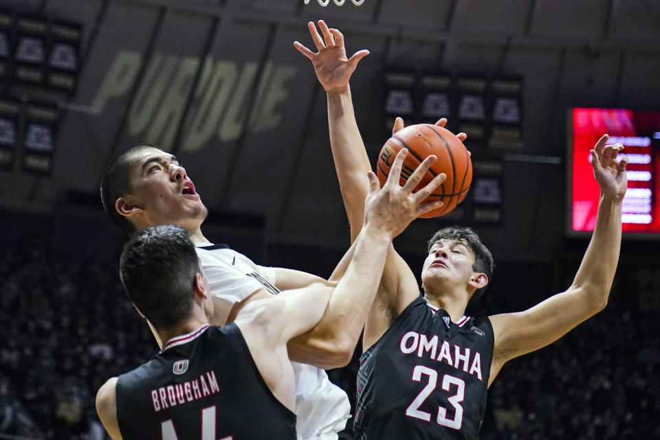 Purdue's Zach Edey (15) is fouled by Omaha's Dylan Brougham (14) and Frankie Fidler (23) as he shoots during the second half of an NCAA college basketball game in West Lafayette, Ind., Friday, Nov. 26, 2021. Purdue defeated Omaha 97-40. (AP Photo/Michael Conroy)