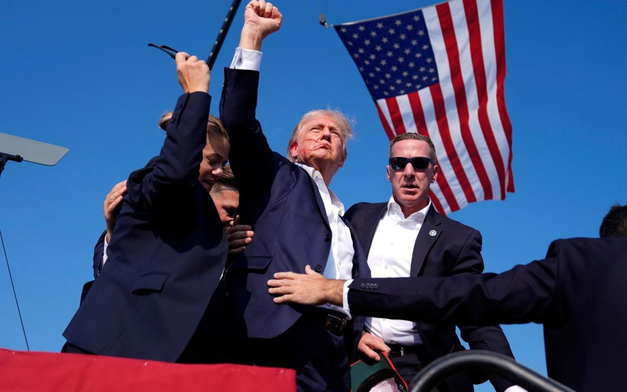 A bloodied Trump holds a defiant fist aloft after the assassination attempt