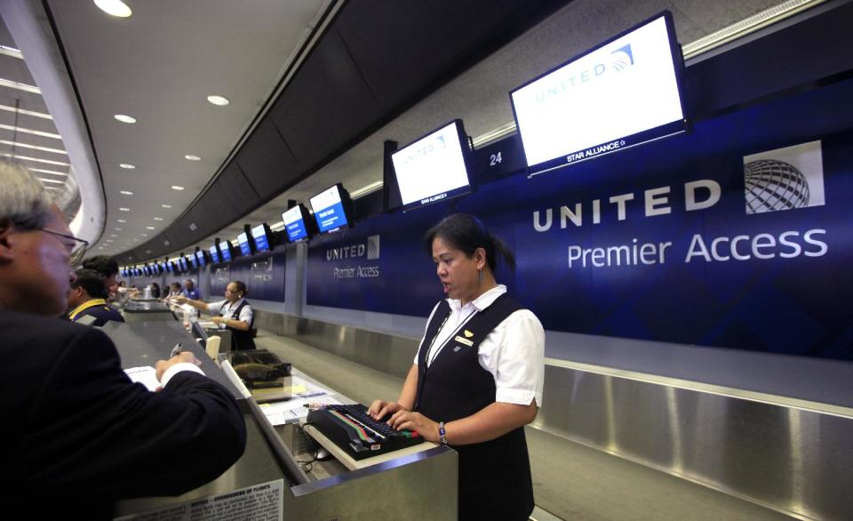 FILE - In this Wednesday, July 13, 2011, file photo, ticket agent Dee Manzon helps a customer at United Airlines premier access check-in counter at San Francisco International Airport in San Francisco. United Airlines said Thursday, Jan. 16, 2014 it will furlough 688 flight attendants after it didn't get enough people to take a voluntary buyout. United has said it wants to cut $2 billion in annual expenses. (AP Photo/Eric Risberg, File)