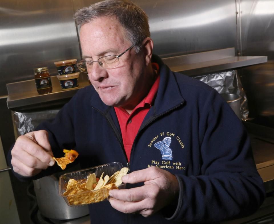 Tom Smith, the chief operating officer of Jar Head Salsa, scoops mild salsa with a chili lime tortilla chip in Davison on Thursday November 29, 2018.