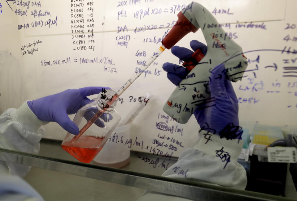 FILE - In this July 30, 2020 file photo, Kai Hu, a research associate transfers medium to cells, in the laboratory at Imperial College in London. Imperial College is working on the development of a COVID-19 vaccine. Refrigeration, cargo planes, and, above all, money: All risk being in short supply for the international initiative to get coronavirus vaccines to the world’s most vulnerable people. (AP Photo/Kirsty Wigglesworth, File)